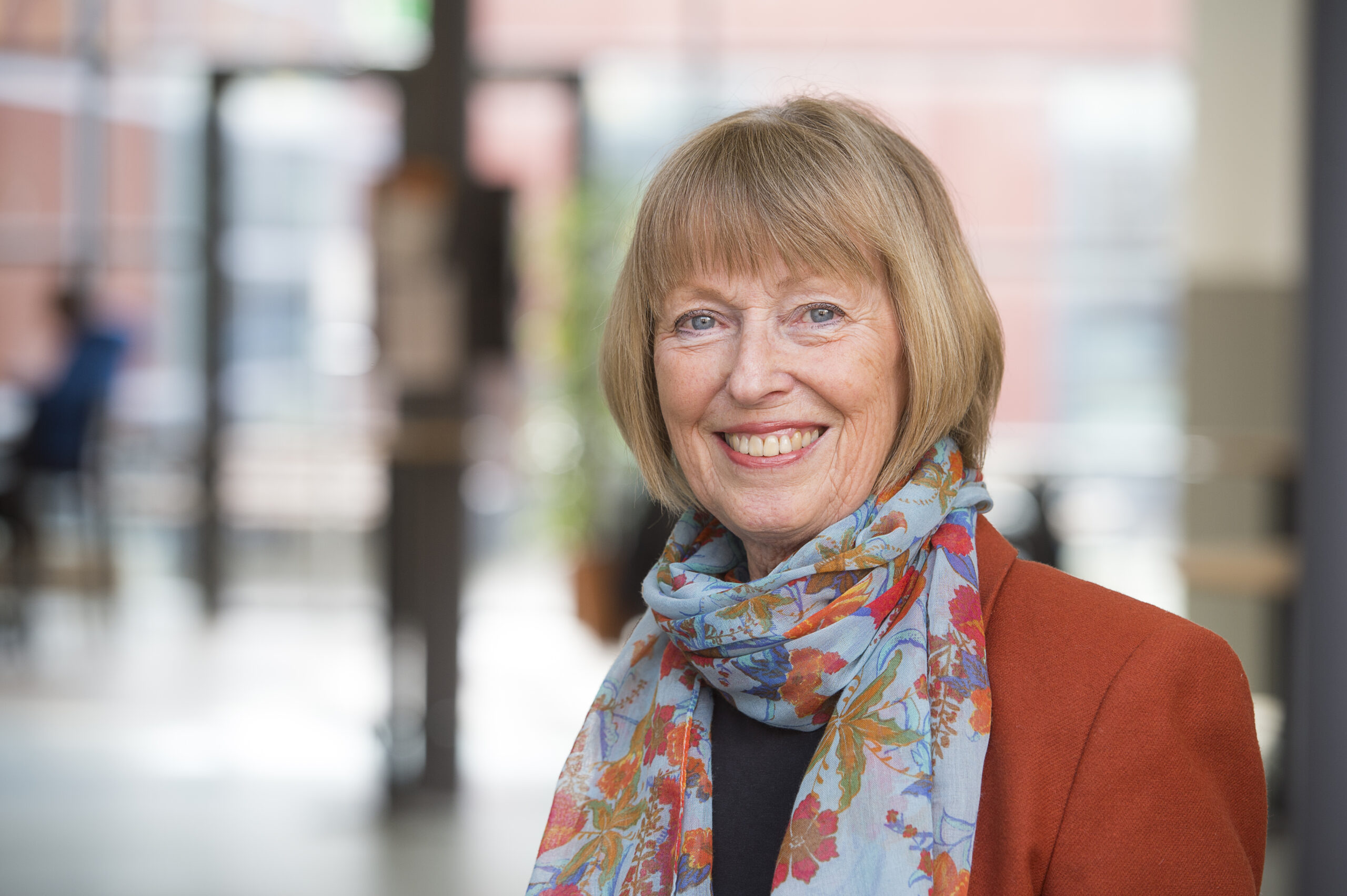 Kvinna med blont hår, bär sjal och orange kavaj. Styrelse.