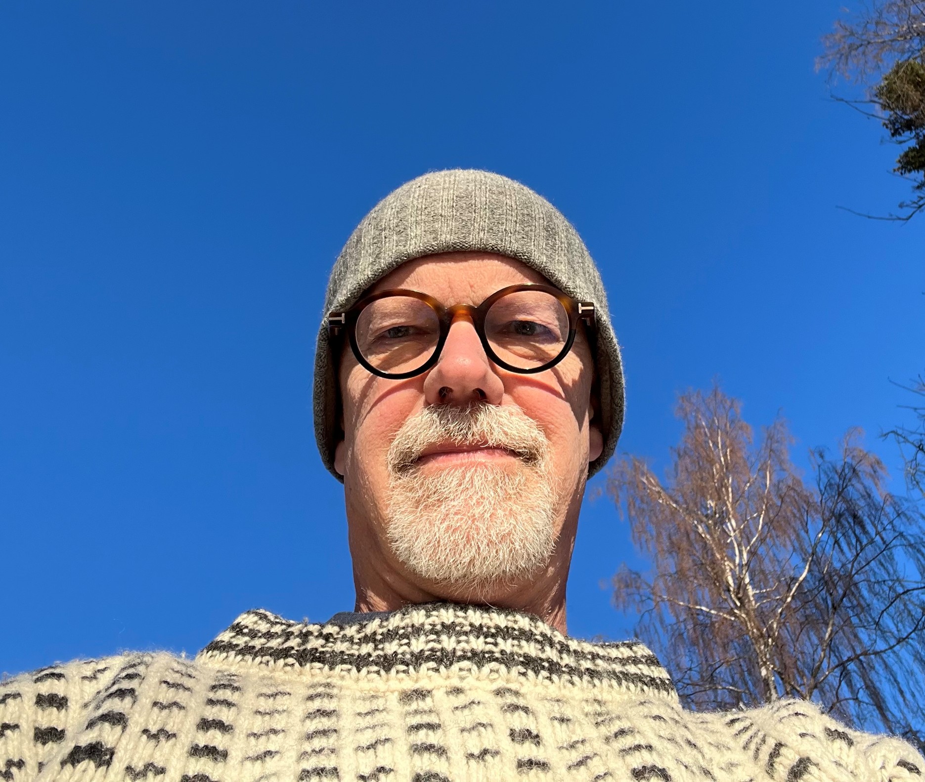 Man med grå mössa och glasögon utomhus. Styrelse.