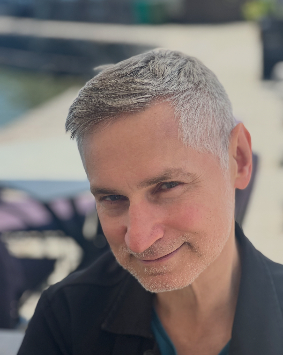 Porträtt av en man med grått hår och ett vänligt leende.