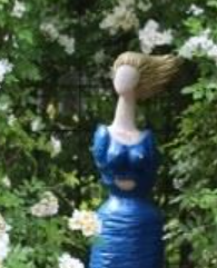 Blå staty i trädgård med vita blommor. Möjligen relaterad till Sveriges konstföreningar.