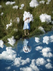 Flicka med moln vid vatten, spegling. Konst från Svenstorp Art Center.