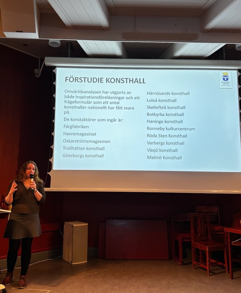 Kvinna presenterar "Förstudie Konsthall" med lista över konsthallar