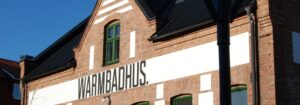 Varmbadhus i Vimmerby, tegelbyggnad med texten "WARMBADHUS" målad på fasaden.